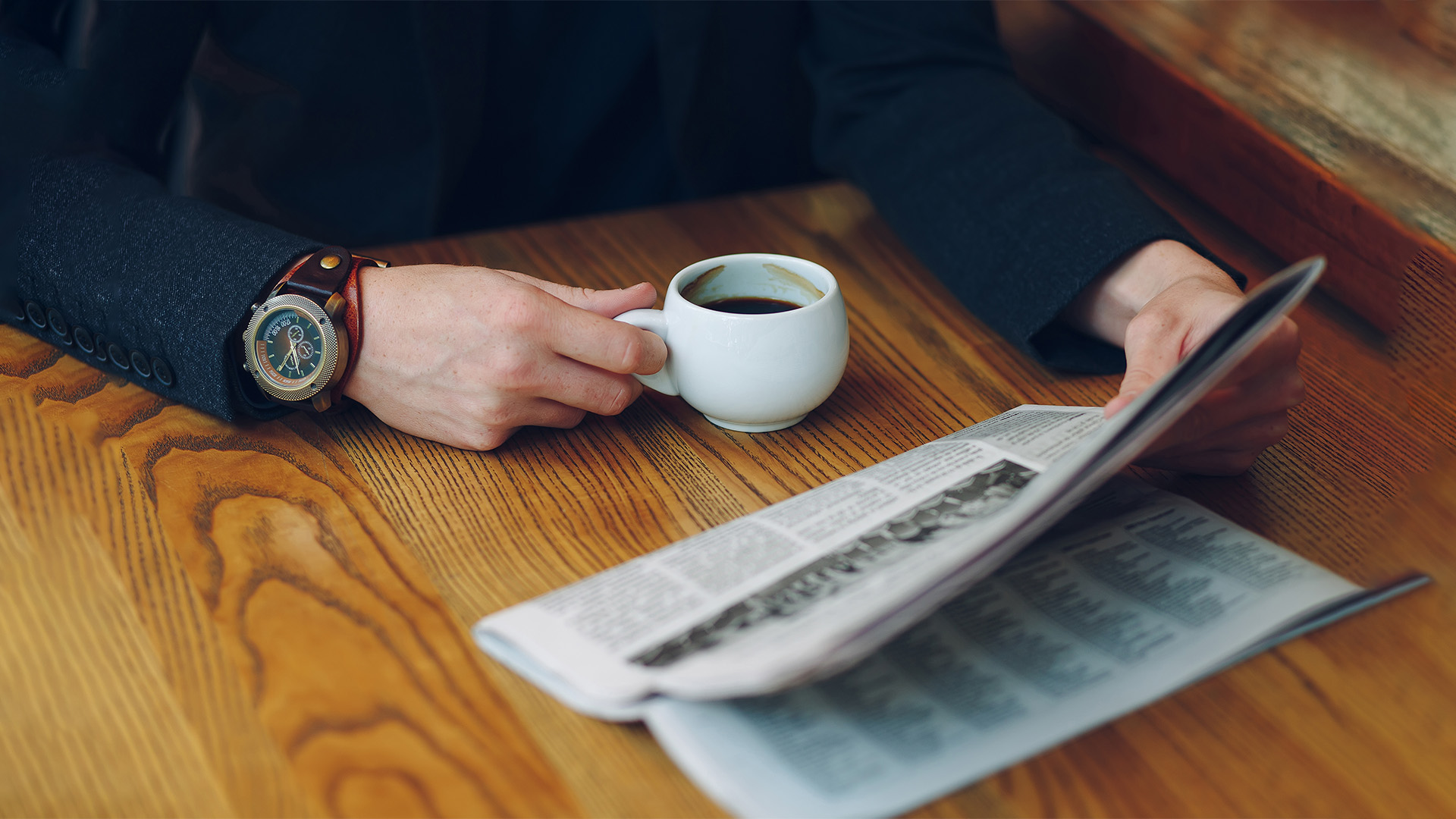 Mann trinkt Espresso und liest Zeitung
