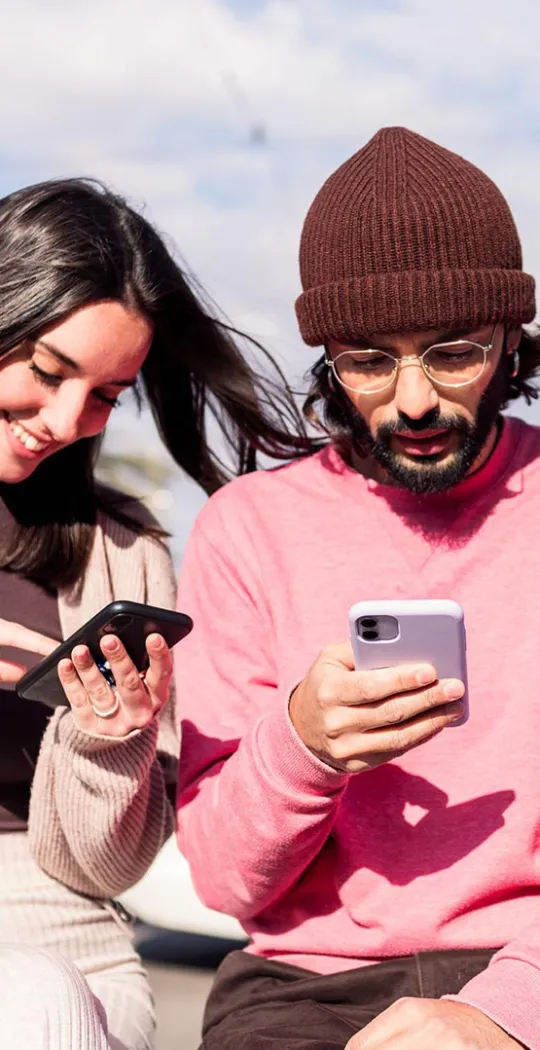 Junge Menschen sitzen zusammen und sind am Smartphone. 