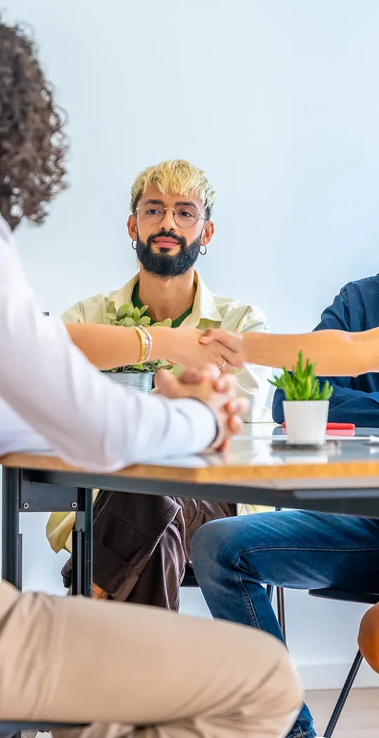 Gruppe junger Menschen sitzt an einem Konferenztisch.