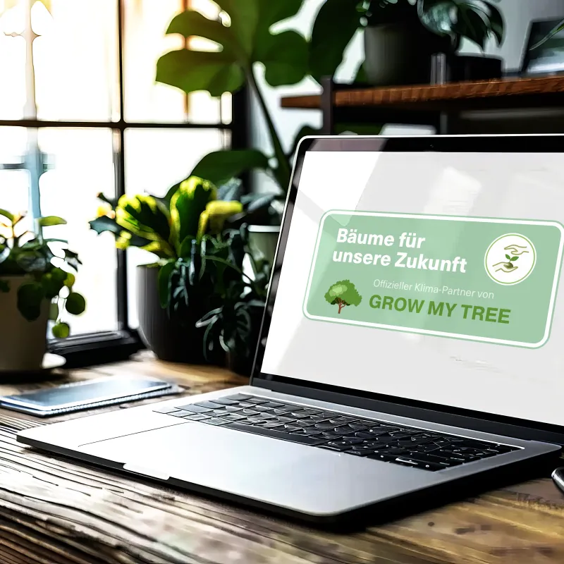 Laptop auf Tisch umgeben von Pflanzen