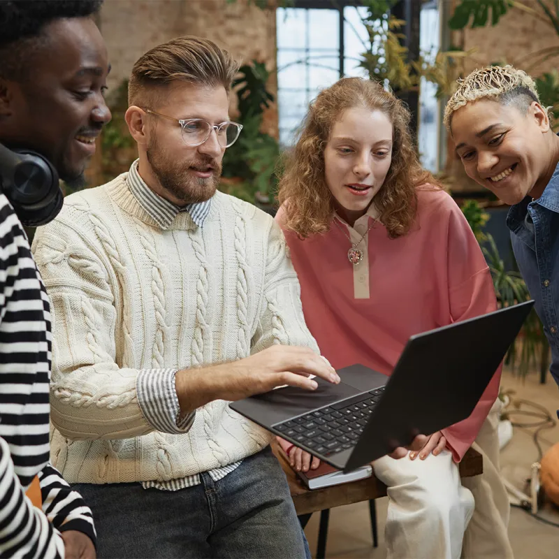 Gruppe von Menschen schaut auf Laptop.