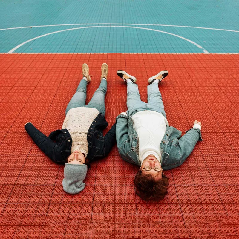 Junges Paar liegt auf dem Boden eines Sportplatzes. 