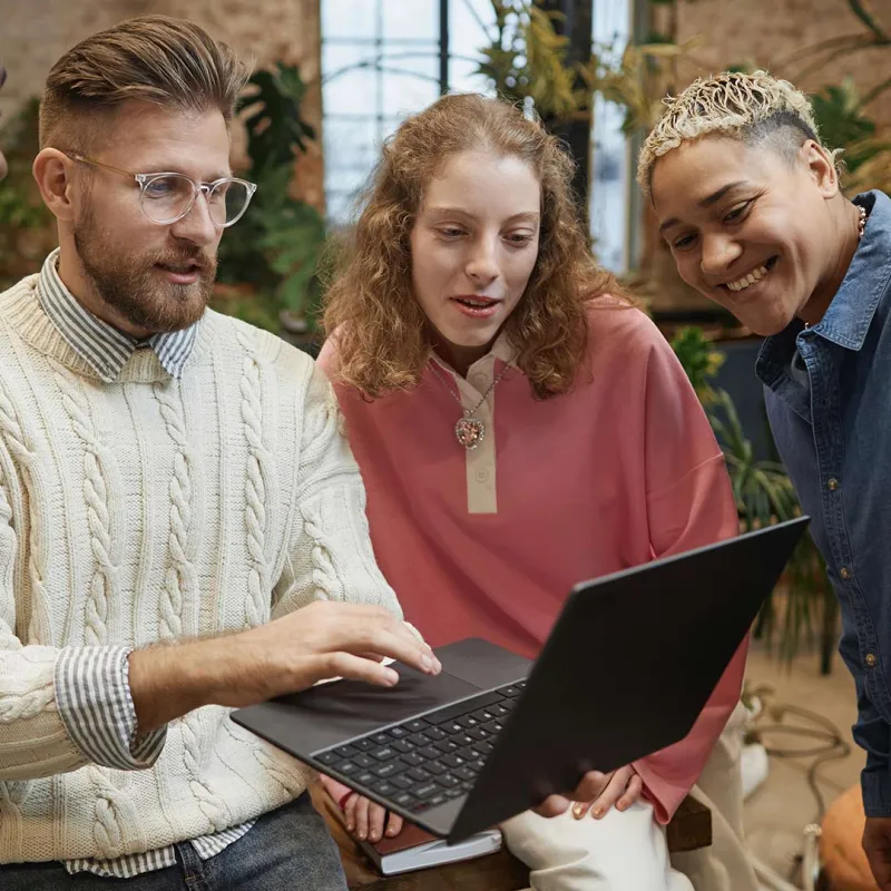 Junge Menschen schauen gemeinsam auf einen Laptop. Junge Menschen schauen gemeinsam auf einen Laptop.