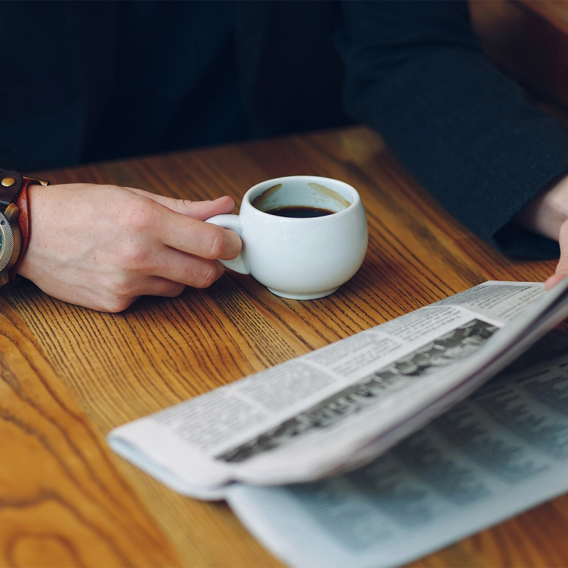 Mann trinkt Espresso und liest Zeitung